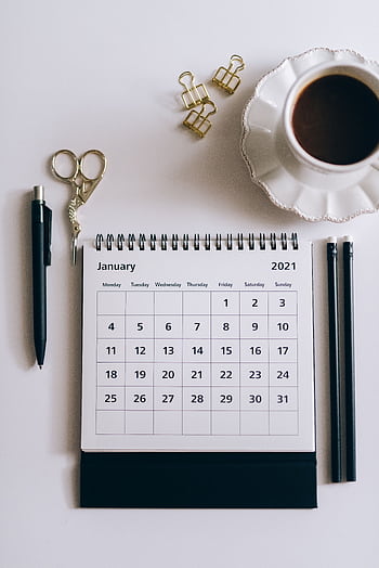 Flat lay of a 2021 desk calendar, coffee cup, and black stationery items on a white surface. HD phone wallpaper