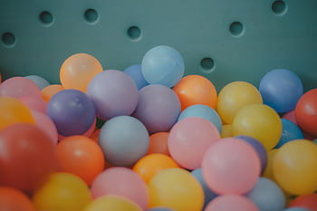 A close-up view of a colorful assortment of plastic balls in a ball pit, showcasing vibrant hues. HD wallpaper