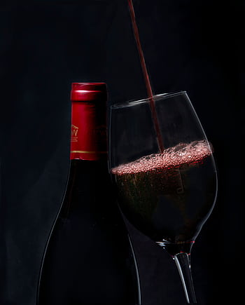 Elegant red wine pouring into a glass with a bottle in background, perfect for wine enthusiasts. HD phone wallpaper
