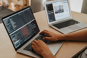 A developer working on a laptop, typing code, showcasing programming and technology skills. HD wallpaper
