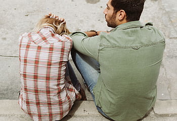A couple sitting on the street, engaged in a distressed conversation, capturing a moment of emotional tension. HD wallpaper