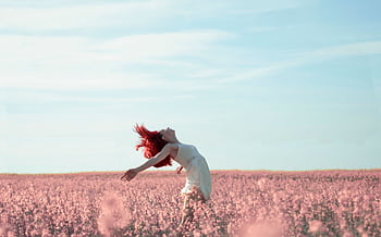 Woman with red hair in a white dress expressing dom in a vibrant summer field. HD wallpaper