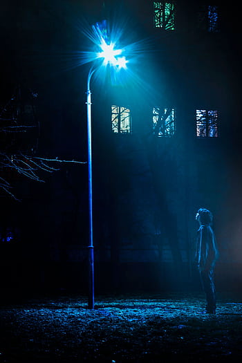 Silhouetted man under a bright streetlight at night, urban scene. HD phone wallpaper