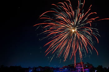 Colorful fireworks illuminating a dark night sky over a silhouetted urban landscape, perfect for celebration themes. HD wallpaper