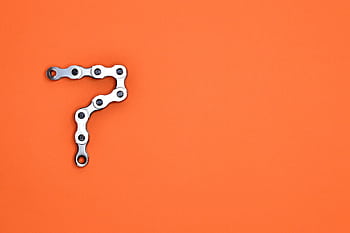 Artistic arrangement of bicycle chain shaped like number seven on orange background. HD wallpaper