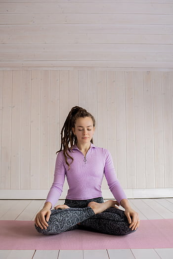Woman practicing yoga meditation indoors on a pink mat, focusing on relaxation and mindfulness. HD phone wallpaper
