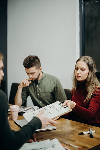 A team of adults discussing documents in an office meeting setting, focusing on collaboration. HD phone wallpaper