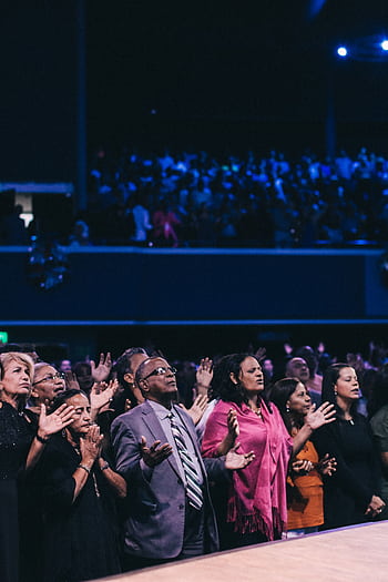 A diverse group of people participating in a lively worship event in a large auditorium. HD phone wallpaper