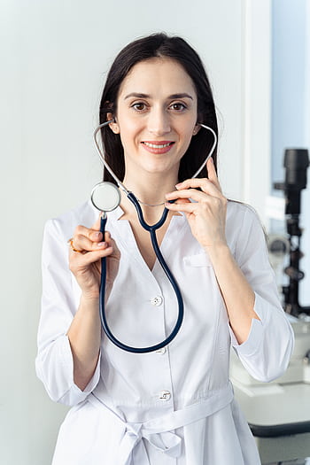 Portrait of a smiling female doctor holding a stethoscope, showcasing professionalism in a healthcare setting. HD phone wallpaper