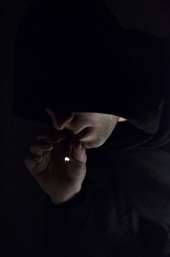 A mysterious individual in a hoodie smoking in the dark, conveying a sense of enigma. HD phone wallpaper
