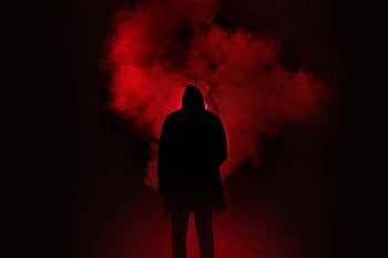 A mysterious silhouette standing against a backdrop of dramatic red smoke. HD wallpaper