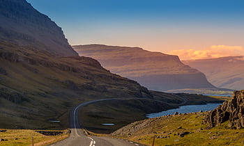 Breathtaking view of an Icelandic road winding through mountains at sunset with vibrant colors. HD wallpaper