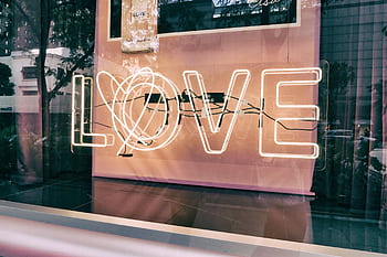 Neon 'LOVE' sign in a modern urban window display with reflections. HD wallpaper