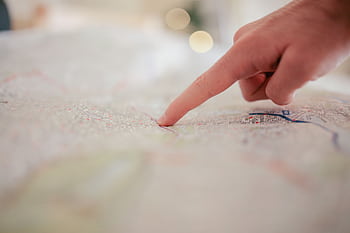 A hand pointing at a city map, highlighting direction and navigation planning. HD wallpaper