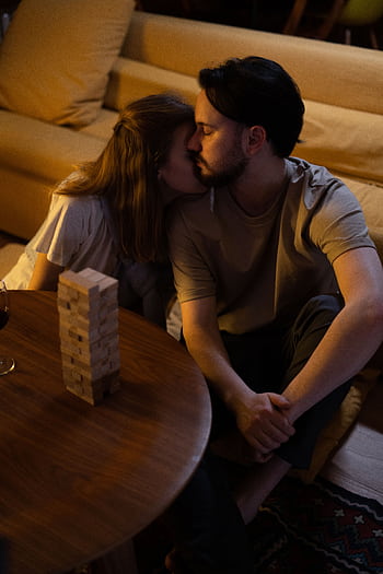 A couple embracing while playing a board game at home in a cozy setting. HD phone wallpaper