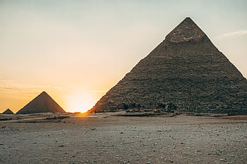 Dramatic sunset view of the iconic Giza Pyramids in Egypt, highlighting their ancient architecture. HD wallpaper