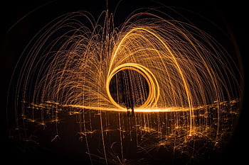 Stunning long exposure shot of steel wool light painting creating bright, glowing arcs in the night. HD wallpaper