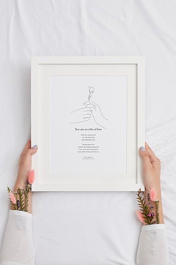 Hands holding a framed inspirational quote on a white background, featuring a minimalist floral illustration. HD phone wallpaper