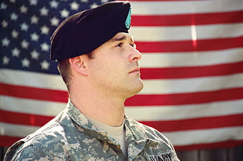 US soldier in uniform stands proudly with the American flag in the background, capturing a sense of patriotism. HD wallpaper