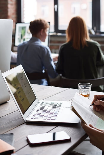 Group of adults working indoors, collaborating with technology, and taking notes for a business project. HD phone wallpaper