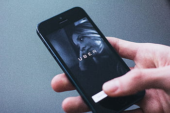 Close-up of a hand holding a smart with the Uber app open on the screen. HD wallpaper