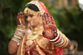 A detailed shot of an Indian bride's henna-decorated hands with traditional jewelry, showcasing cultural richness. HD wallpaper