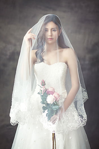Graceful bride in lace dress holding a rose bouquet and wearing a veil. HD phone wallpaper
