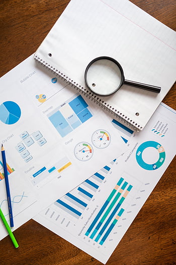A set of financial charts and graphs with a magnifying glass, perfect for business reports. HD phone wallpaper