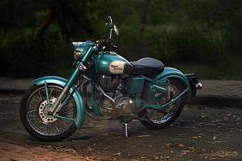 Classic Royal Enfield motorcycle parked peacefully in an outdoor setting, representing vintage style and timeless engineering. HD wallpaper
