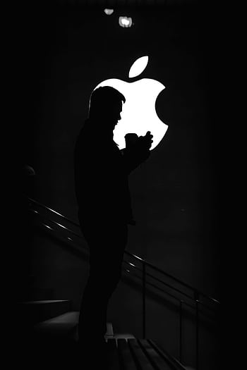 Silhouetted man against bright Apple logo, creating dramatic contrast. HD phone wallpaper