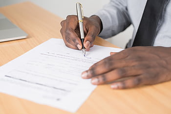 Close-up of a businessman signing a contract at an office desk. HD wallpaper