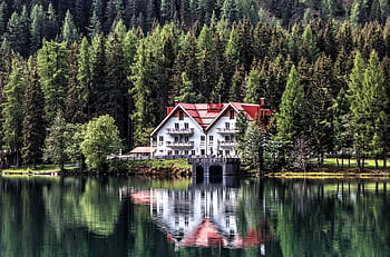 Charming chalet nestled by a serene lake with lush forest backdrop, showcasing perfect reflection. Ideal for nature lovers. HD wallpaper