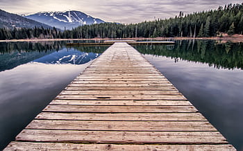 A peaceful view of a wooden dock leading to a mountain lake in Whistler, BC, Canada. HD wallpaper