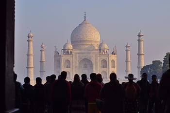 Silhouetted tourists admire the Taj Mahal's iconic beauty at sunrise, a UNESCO World Heritage site. HD wallpaper