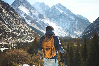 A lone hiker with a backpack explores a scenic winter mountain landscape. HD wallpaper
