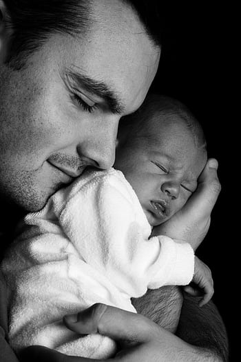 A father lovingly embraces his newborn. Monochrome portrait capturing family warmth. HD phone wallpaper