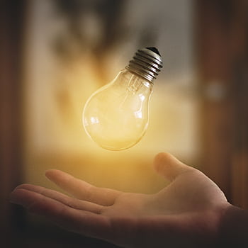 A glowing light bulb hovers above an open hand, symbolizing innovation and creativity. HD phone wallpaper