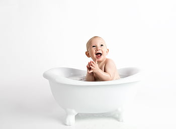 Cute baby laughing and clapping in a white bathtub against a white background. HD wallpaper