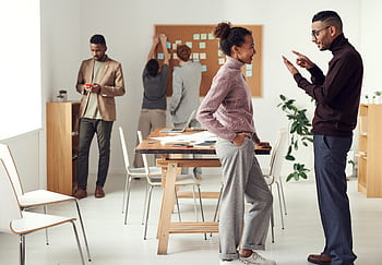 Colleagues engaging in teamwork and brainstorming in a modern office space. HD wallpaper