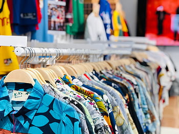 A vibrant collection of Hawaiian shirts on hangers in a clothing store with varied designs and colors. HD wallpaper