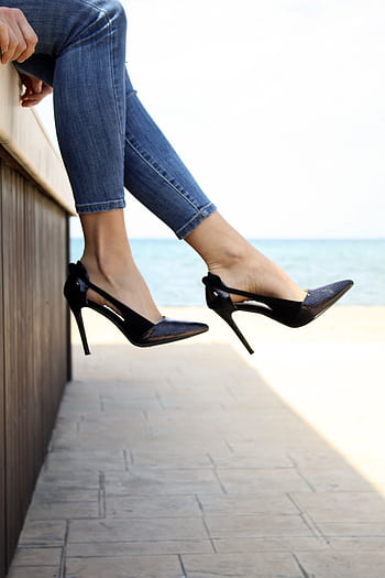 Stylish high heels with jeans against a serene seaside background in Thessaloniki. HD phone wallpaper