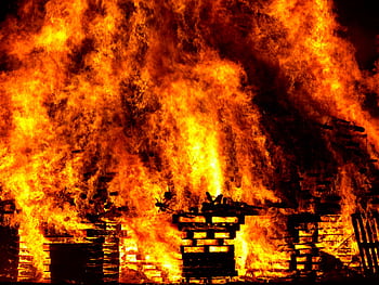 Intense flames engulf wooden pallets in a breathtaking display of fire and heat. HD wallpaper