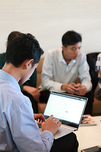 A group of colleagues in a business meeting using laptops for planning and teamwork. HD phone wallpaper