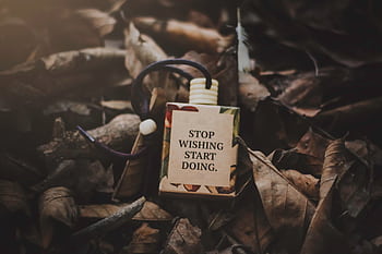 A box with a motivational quote amid dry autumn leaves, inspiring action. HD wallpaper