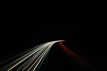 Dynamic long exposure capturing light trails on a dark highway at night. HD wallpaper