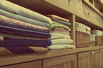 Tidy wooden cabinet with neatly stacked towels and decorative baskets in an indoor setting. HD wallpaper