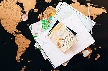 A flat lay of travel planning items on a map, featuring a compass, notebook, and guide for wanderlust enthusiasts. HD wallpaper