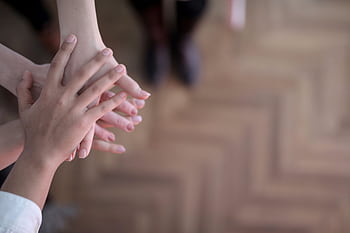 Hands stacked showing teamwork and unity from a top view indoors. HD wallpaper