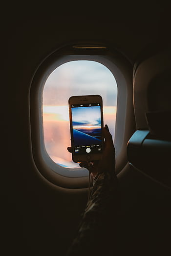 A person takes a of a sunset through an airplane window using a smart. HD phone wallpaper
