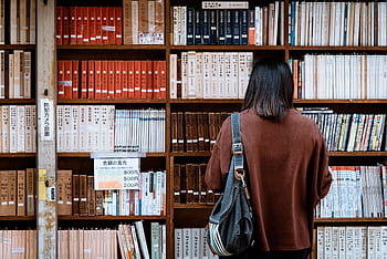 Woman browsing books at a library in Nagano, Japan. Explore knowledge and literature. HD wallpaper